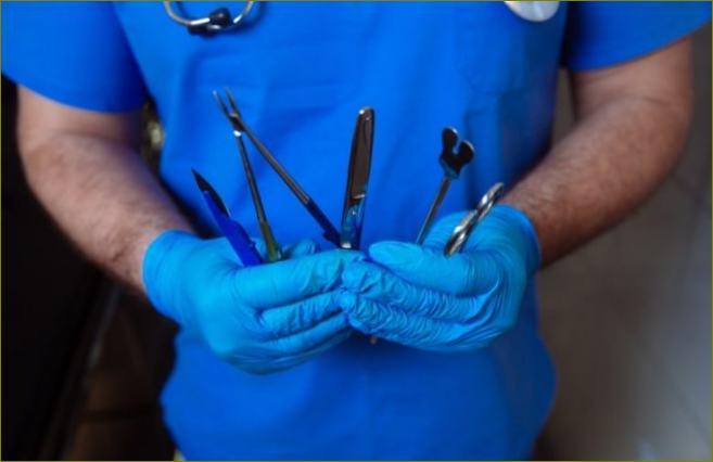 Лекар държи хирургически инструменти